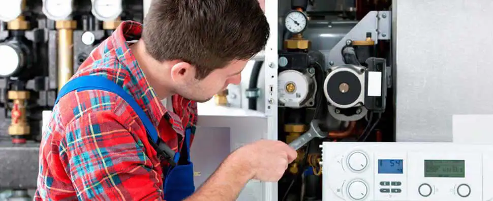 A technician makes adjustments on an HVAC unit